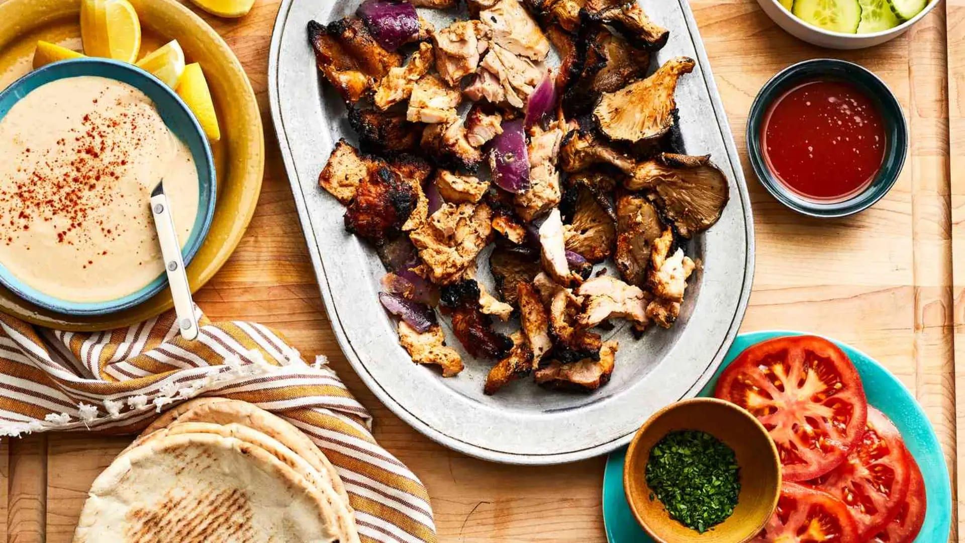 Chicken shawarma platter with tomatoes, pita and sauces